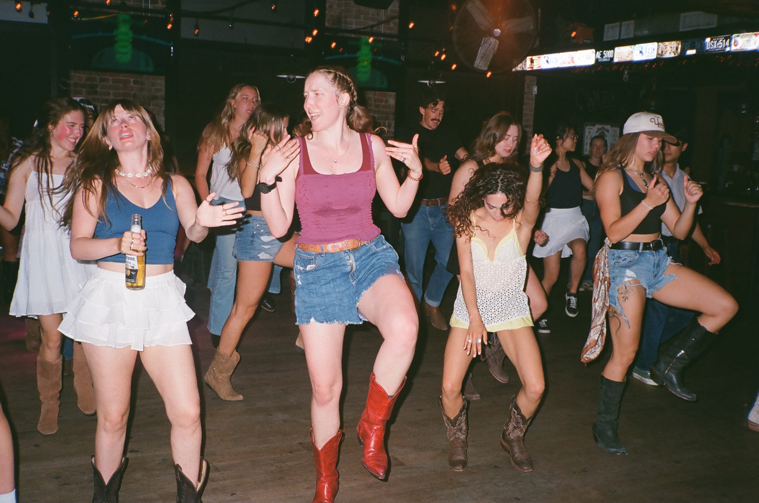 Dancers in cowboy boots mid-step on a wooden dance floor