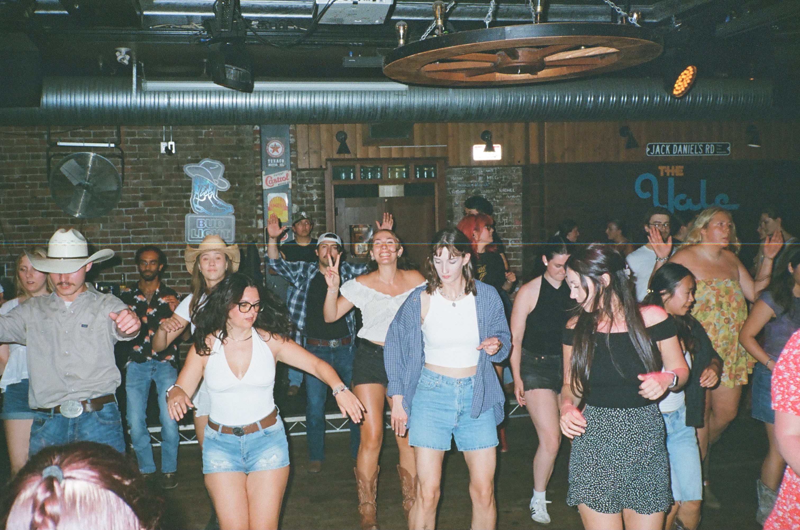 A packed dance floor line dancing together at a country bar