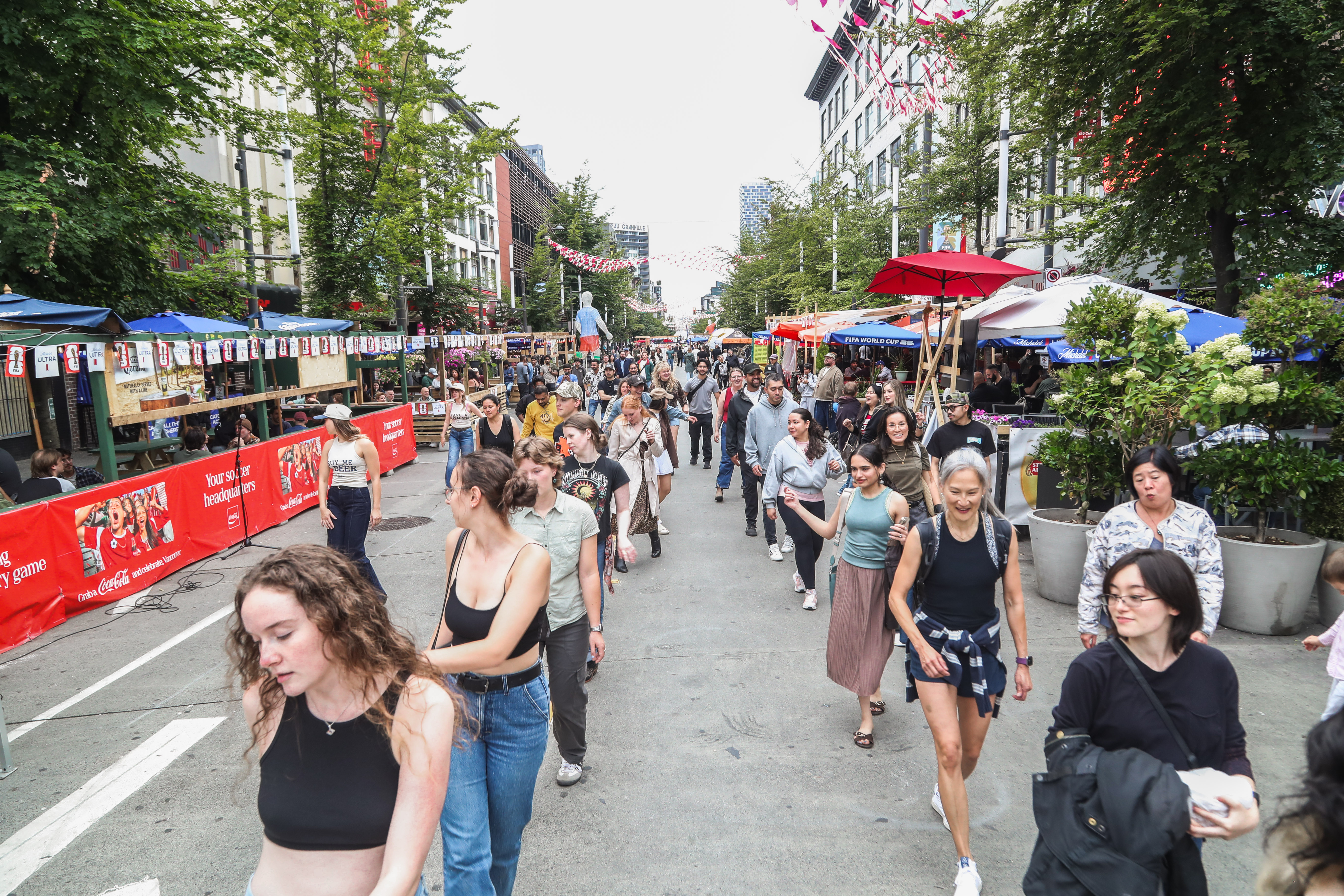 Dozens of people joining a line dance down a festival street in Vancouver