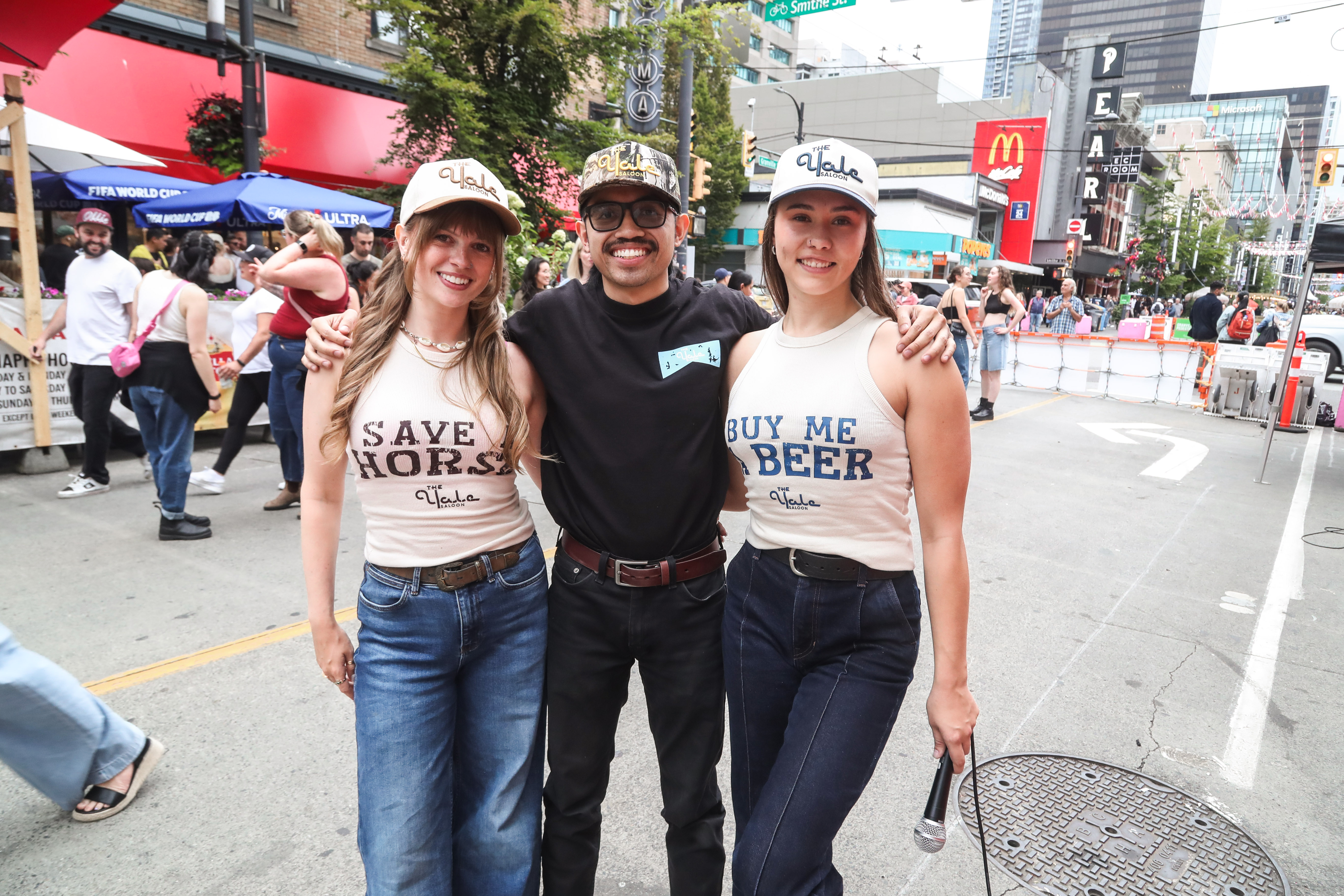 Three dancers smiling arm in arm at a street festival