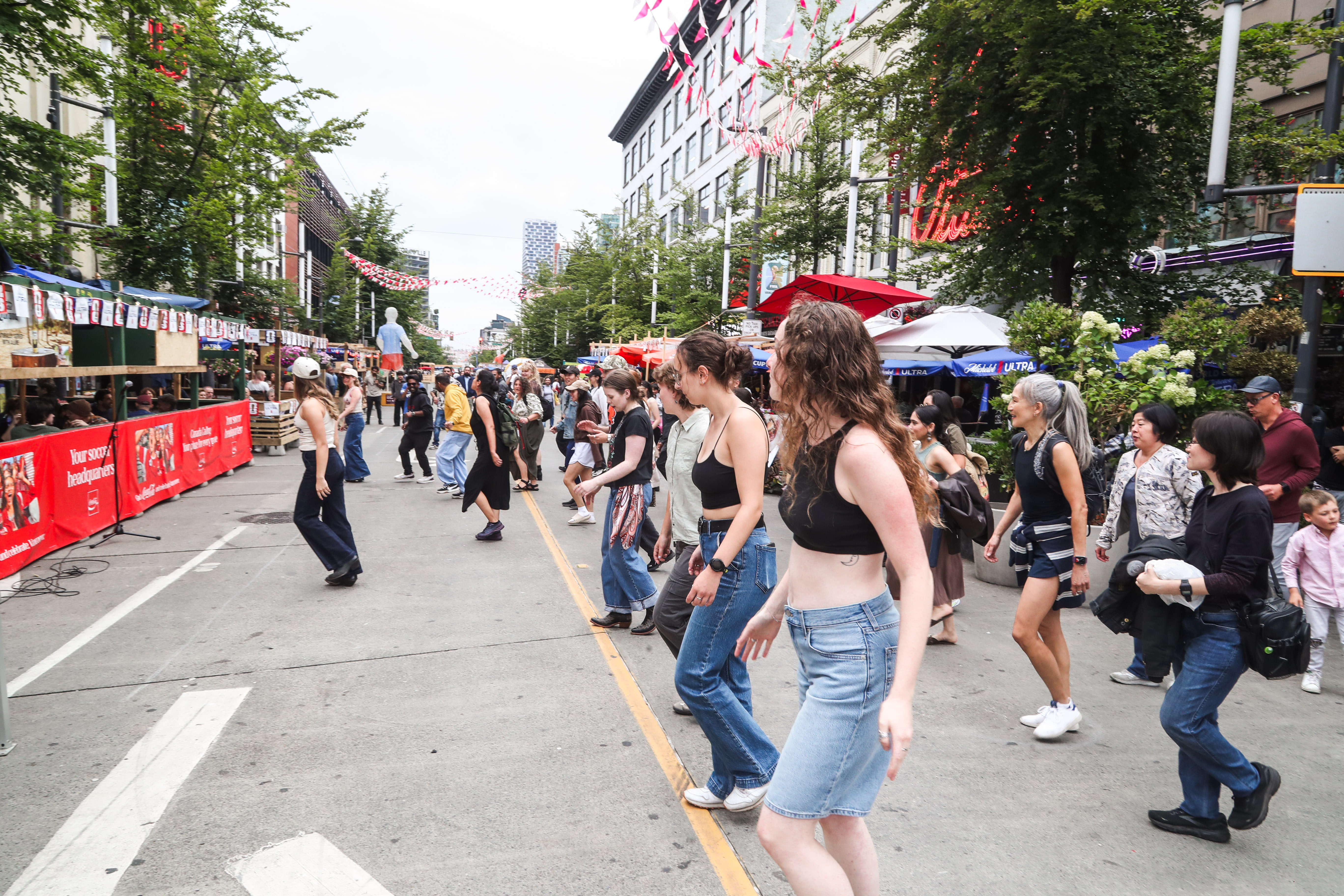 A crowd line dancing together on a closed downtown Vancouver street